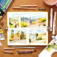 an open book sitting on top of a wooden table next to markers and pencils