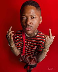 a man with tattoos on his arms and chest posing for a photo in front of a red background