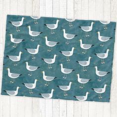 a teal background with seagulls on it and white wood planks in the background