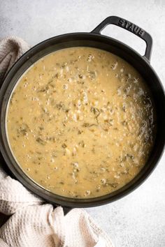 a pot filled with soup sitting on top of a white counter next to a pair of gloves