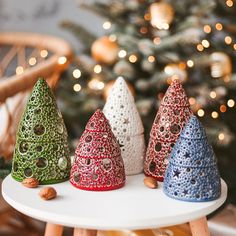 three small christmas trees sitting on top of a white table next to a christmas tree