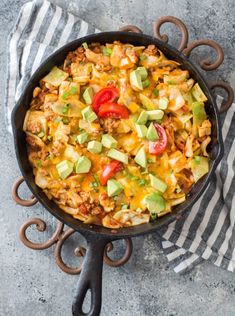 a skillet filled with taco salad on top of a striped towel next to a fork