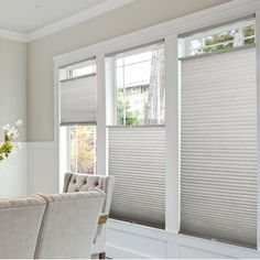 a living room with two couches and three windows that have blinds covering them in shades