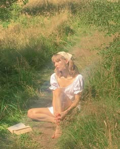 a woman sitting in the grass with a book