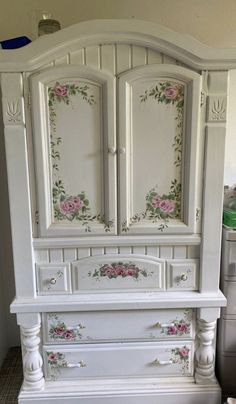 a white armoire with pink flowers painted on it