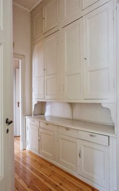 an empty kitchen with white cabinets and wood floors