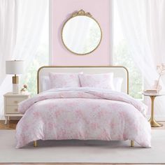 a bedroom with pink walls and white bedding in front of a round mirror on the wall