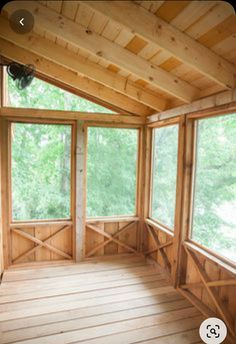 an empty room with large windows and wood paneling on the walls, in front of trees