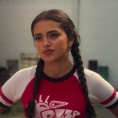 a woman with long braids wearing a red and white shirt is posing for the camera