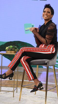 a woman sitting on top of a chair in front of a blue screen and smiling