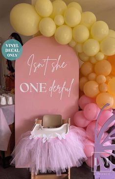 a baby's first birthday party with balloons and decorations, including a pink chair