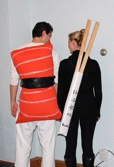 a man and woman dressed up in costumes with baseball bats on their backs, standing next to each other