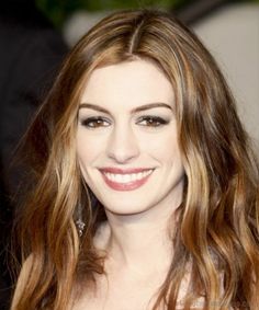 a close up of a person with long hair and brown eyeshadow smiling at the camera