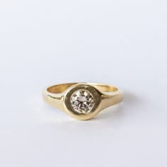 a yellow gold ring with a single diamond in the center, on a white background