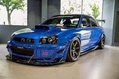 a blue sports car parked in a garage with its hood up and front bumper down