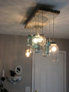 mason jar chandelier hanging from the ceiling in front of a door with lights on it