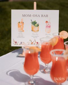 cocktails are lined up on a table with a sign that says mom - osa bar