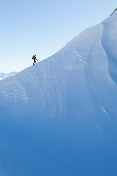 a person is skiing down a snowy mountain side with mountains in the background and blue sky