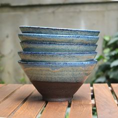 a stack of blue and brown bowls sitting on top of a wooden table