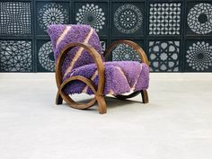 a purple chair sitting on top of a white floor next to a wall with intricate designs