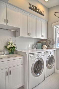 a washer and dryer in a white laundry room with lots of cabinet space