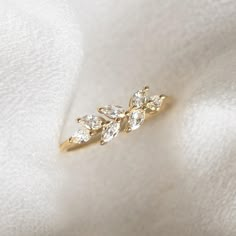 a gold ring with three small diamonds on top of white fabric, close - up