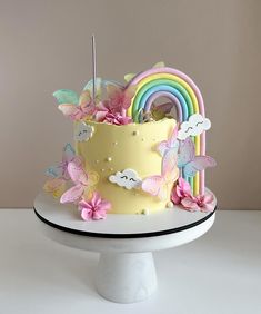 there is a yellow cake with butterflies and rainbows on the top that has been decorated