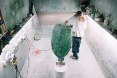 a man is holding a surfboard in a room with concrete walls and flooring