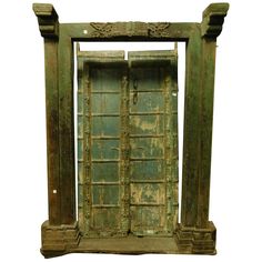 an old green door is open on a white background and there are two pillars in front of it