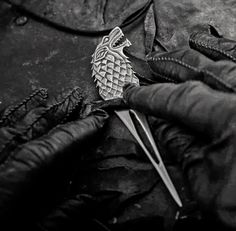 a black and white photo of a pair of gloves with a fish brooch on it