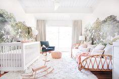 a baby's room decorated in pastel tones with trees and foliage on the wall