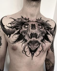 a man with tattoos on his chest is wearing a demon head and wings tattoo design