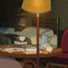 a lamp that is sitting on top of a table in front of a bed and some books