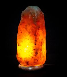 a large orange rock sitting on top of a black table next to a lit candle