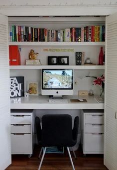 a desk with a computer on top of it in front of a bookshelf