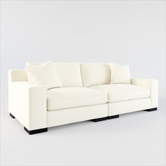 a white couch sitting on top of a white floor next to a gray wall with black legs