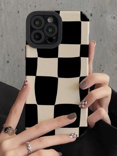 a woman holding up her phone case with black and white checkerboard on it