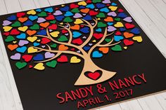 a wedding guest book with hearts and a tree on the cover is sitting on a white wood floor