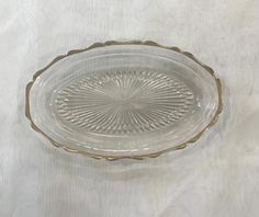 a clear glass dish with gold trim on a white tableclothed surface, in the shape of a sunburst