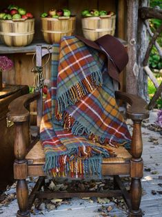 a plaid blanket sitting on top of a wooden chair in front of potted plants