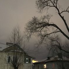 the sky is very dark and overcast with some snow on the ground in front of houses