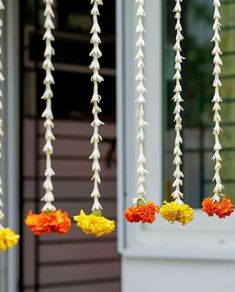 flowers hanging from strings in front of a house