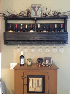 a shelf with wine glasses on top of it next to a cabinet filled with bottles and glasses