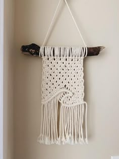 a white macrame hanging on a wall next to a piece of driftwood