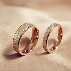 two gold wedding rings with glitter on them