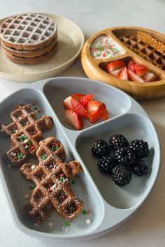 waffles, berries and other food items are arranged in separate trays on a table