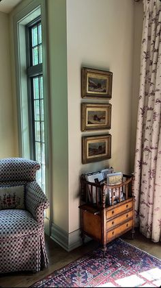 a living room filled with furniture and paintings on the wall next to a window covered in curtains