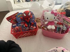 two baskets filled with toys sitting on top of a bed next to a stuffed animal