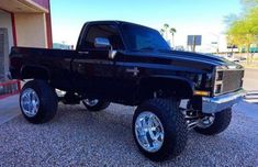 a black pickup truck parked in front of a building with chrome rims and tires