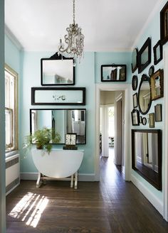 a bath room with a tub a mirror and pictures on the wall